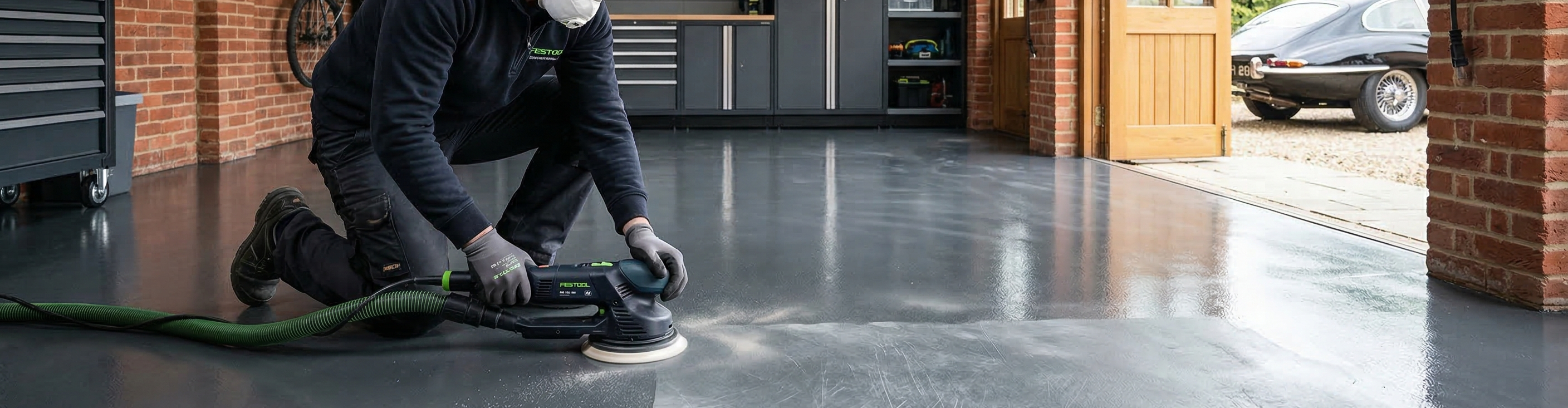 Sanding an existing epoxy floor with an orbital sander to create a mechanical key for a new topcoat.